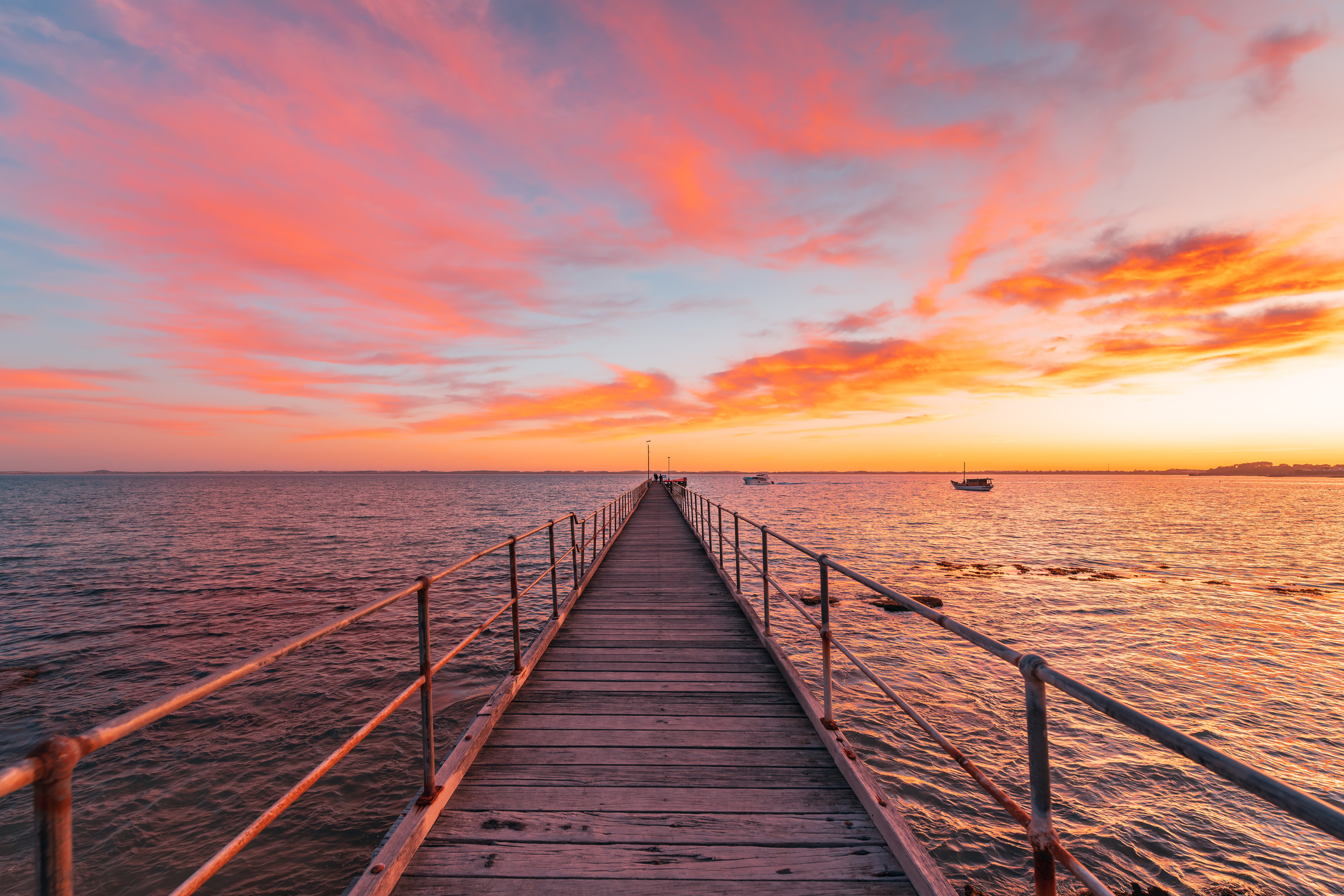 Robe jetty with fishermen during sunrise while viewed towards the ocean from the shore